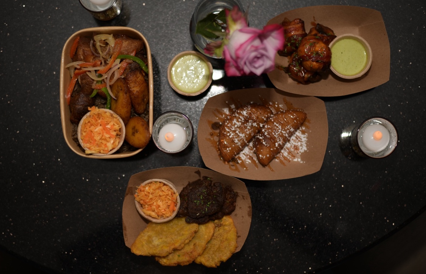 Spread of Caribbean dishes with fried pork, plantains, and pikliz